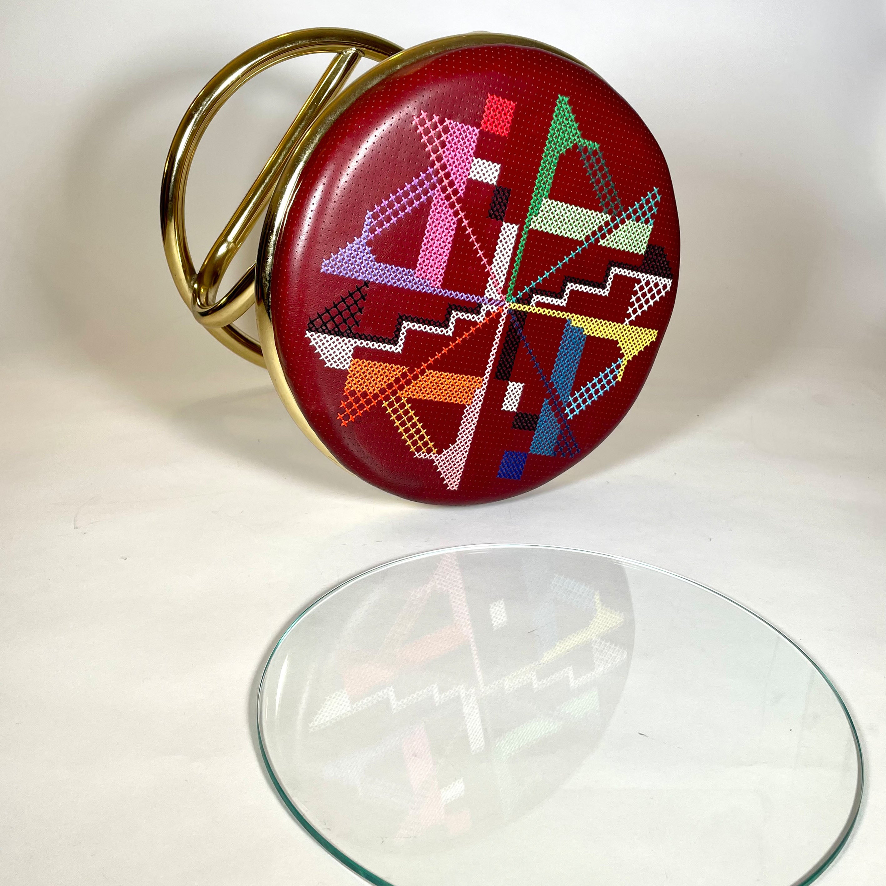 Hocker mit goldenem Metallgestell und aufwändig besticktem Sitzpolster aus Leder in Bordeaux bunt bestickt Beistelltisch mit Stickerei und Glasplatte